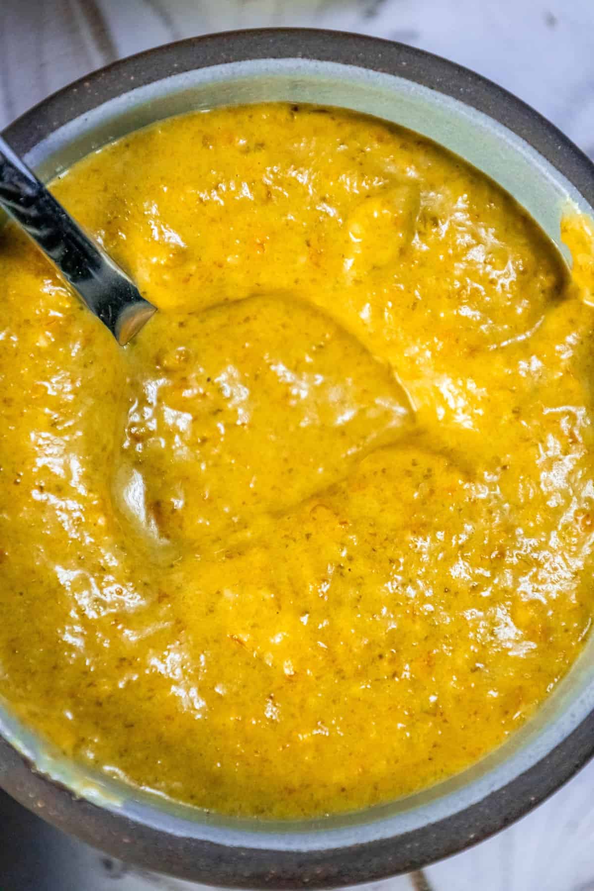 A bowl of yellow Habanero sauce with a spoon in it.