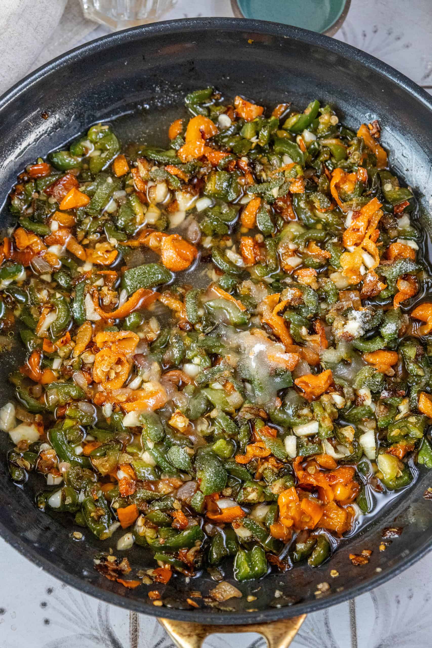 A fiery frying pan sizzling with vegetables drenched in Habanero-infused hot sauce.