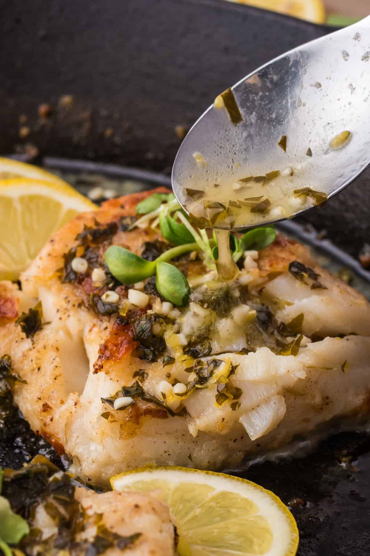 Cooking fish fillets with lemon and herbs in a skillet.