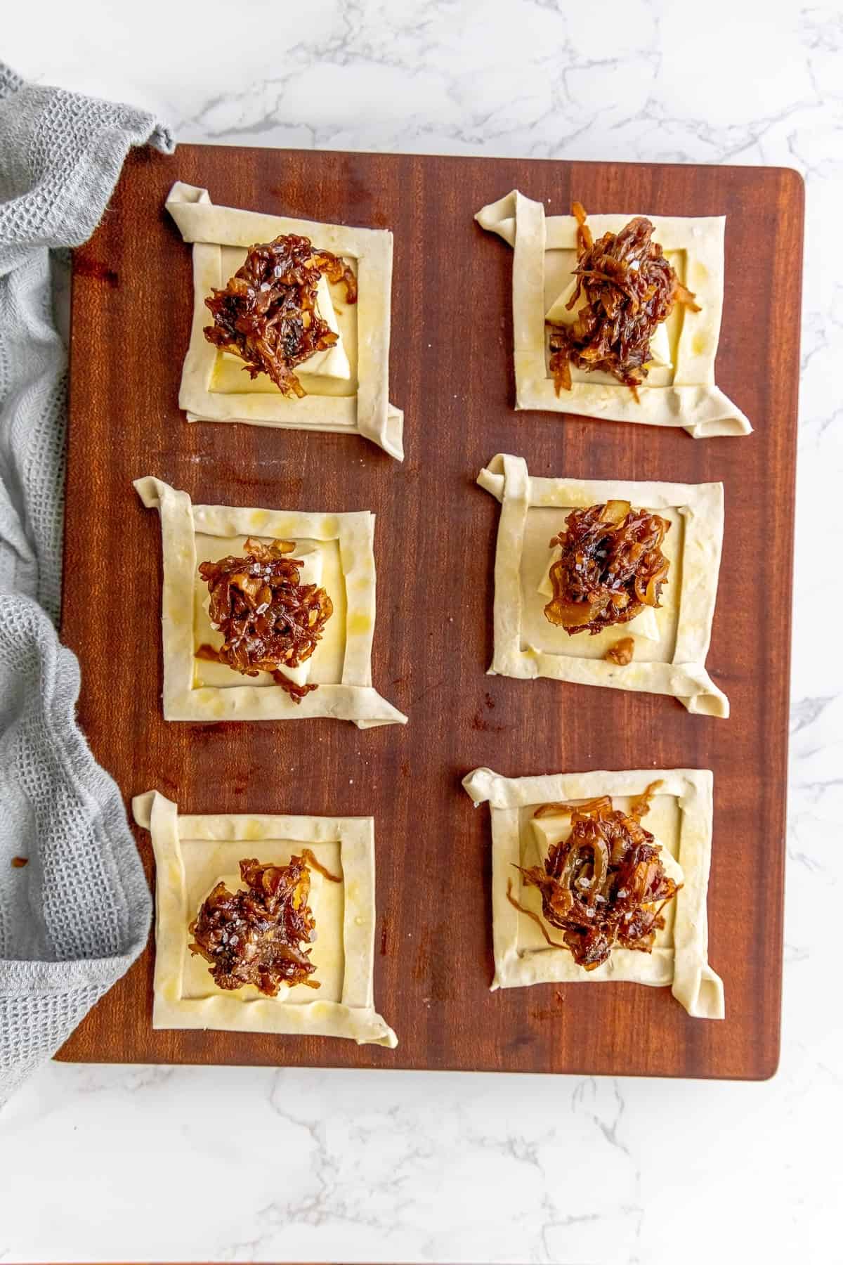 A wooden cutting board with a tray of pastries on it.