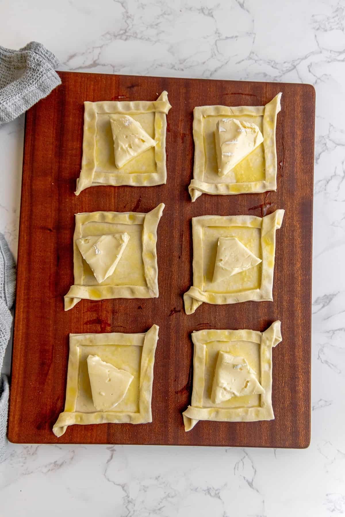 A wooden cutting board with a bunch of pastry squares on it.