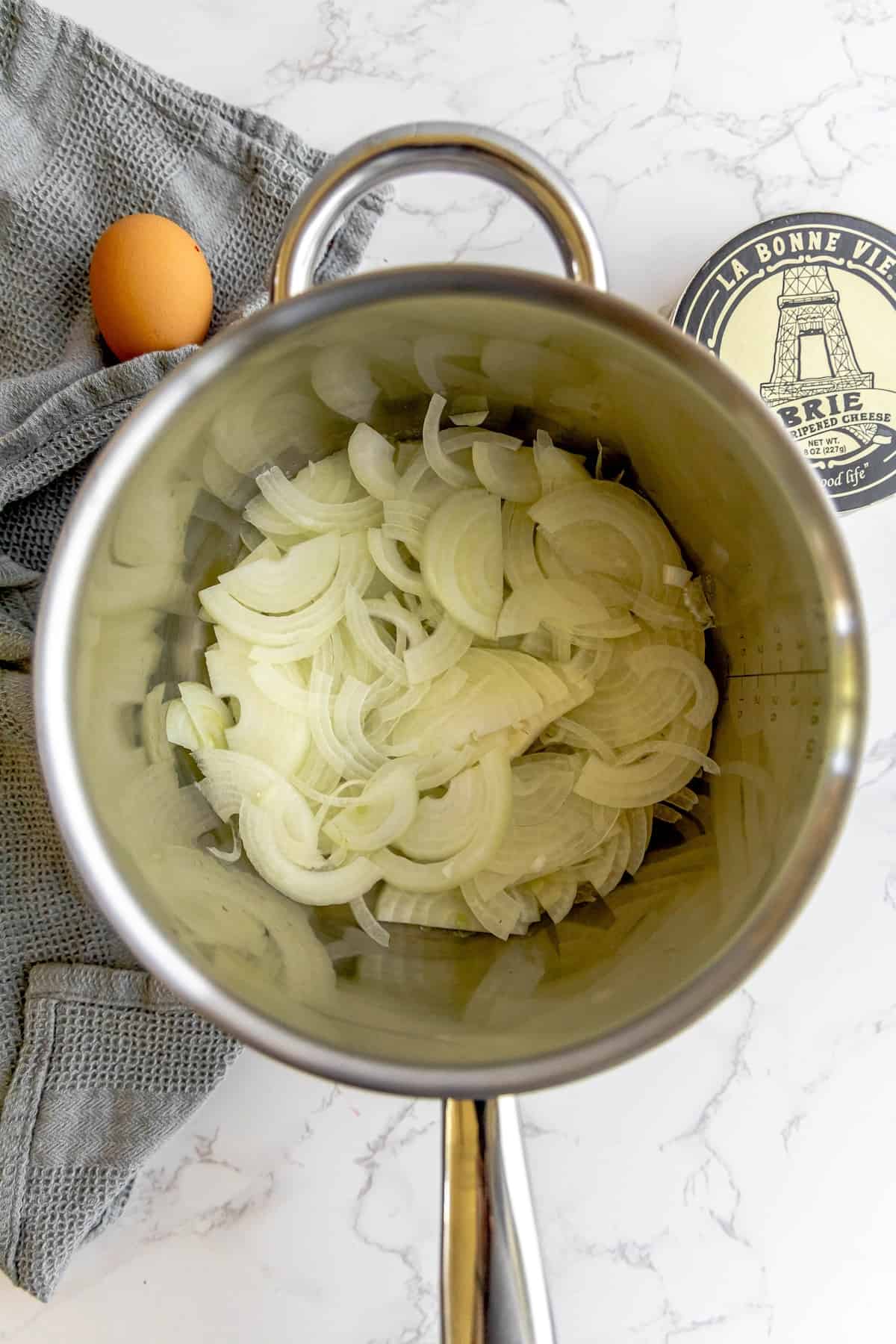 A pot with onions and an egg in it.
