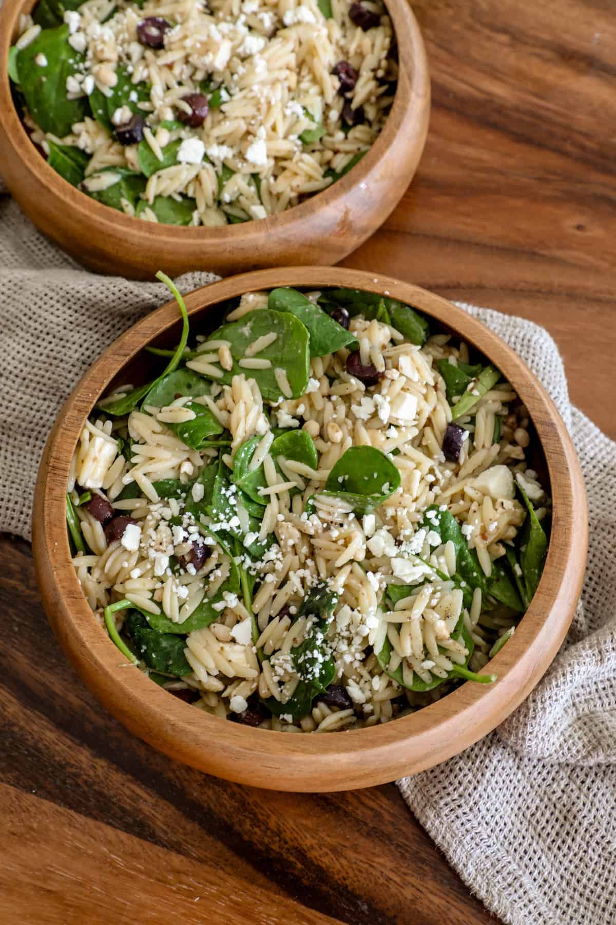 Two wooden bowls of feta and orzo salad.