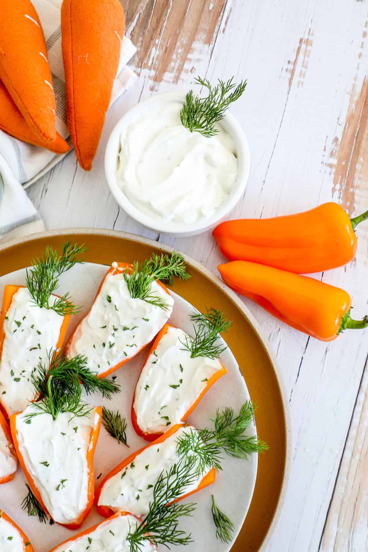 A plate of carrots with goat cheese and dill on it.
