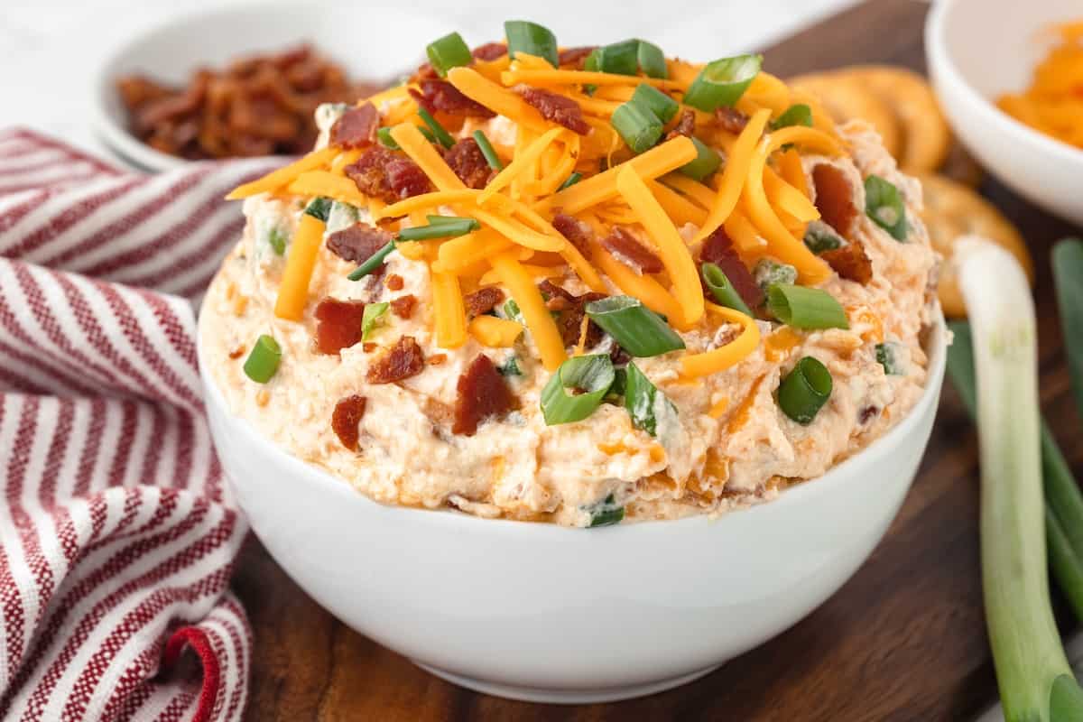 Million Dollar Buffalo Chicken Dip served as an appetizer in a white bowl on a cutting board.