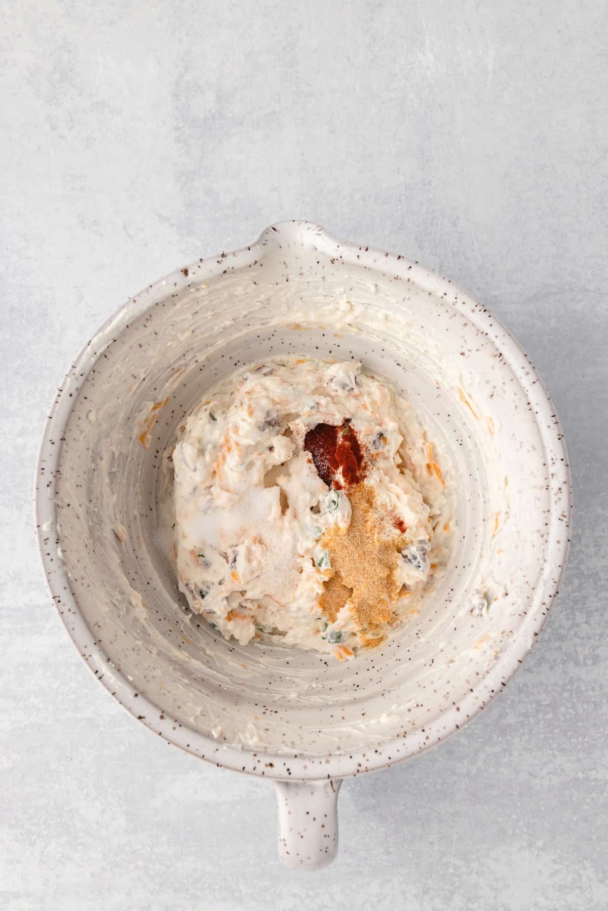 A bowl of hummus, an appetizer, on a grey background.