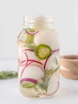 A mason jar filled with sliced radishes and dill.