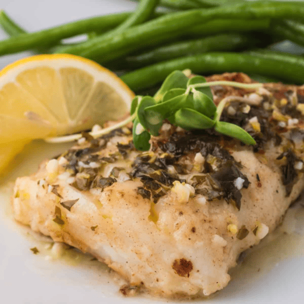 A plate of food with lemon and green beans served alongside easy pan fried cod.