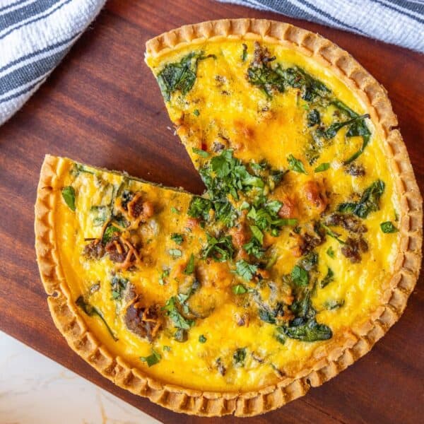 A sausage and spinach quiche with a slice missing.