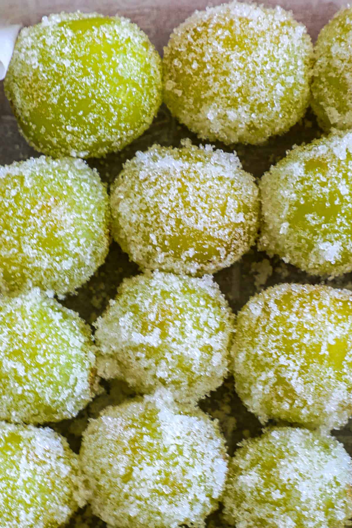 Close-up of sugared green candies piled together, with focus on their textured sugar coating.
