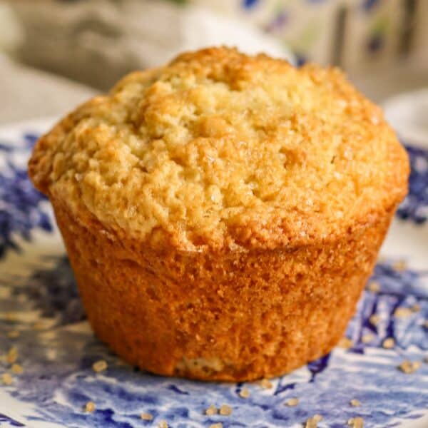 A close-up of a golden-brown muffin on a blue floral-patterned plate.
