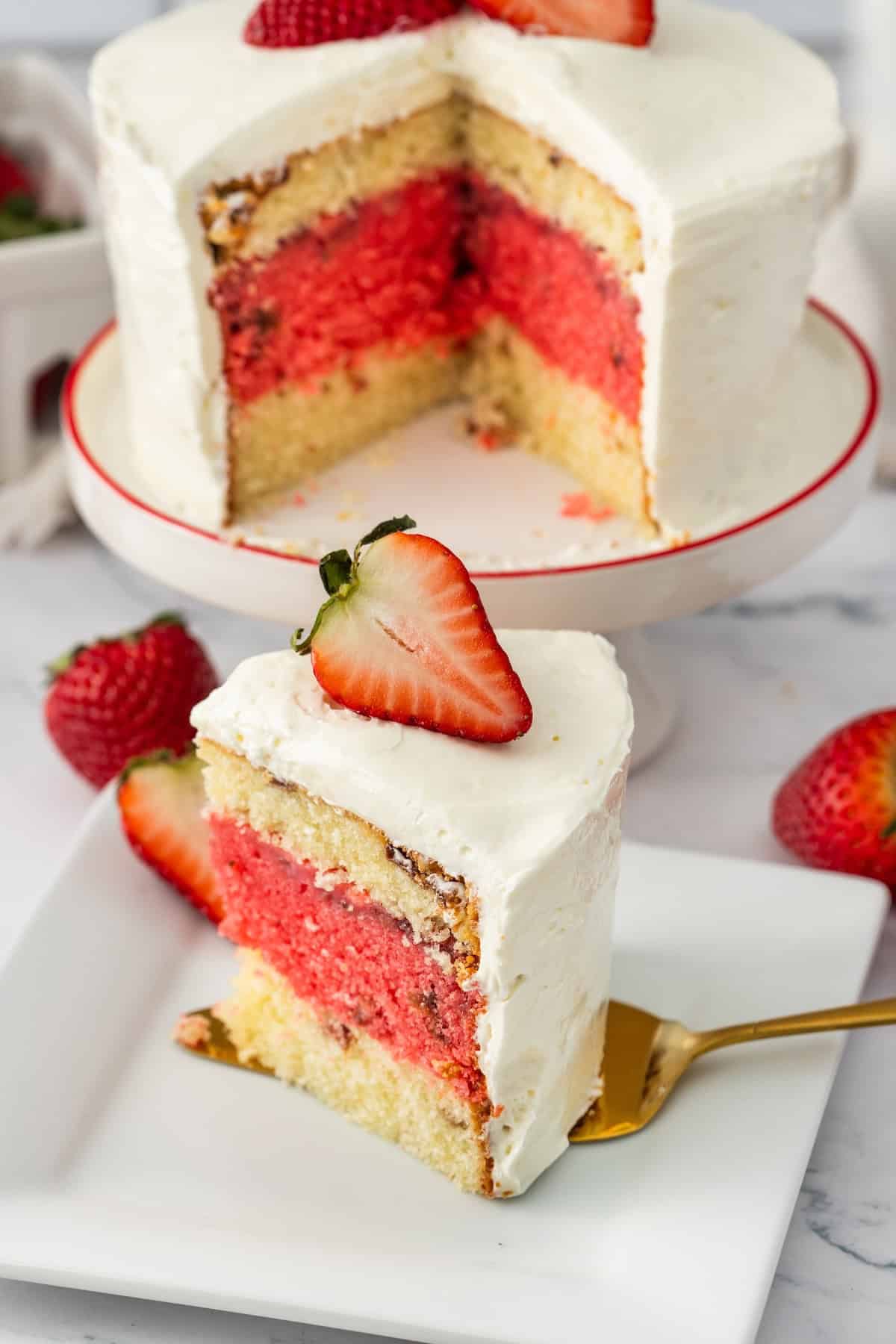 cake with two layers of vanilla one os strawberry with white frosting and a strawberry on top