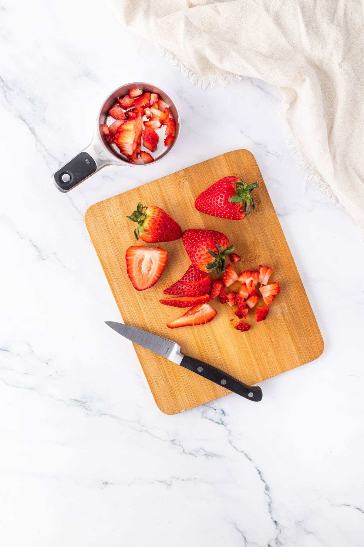 strawberries on a board with some in a measuring cup