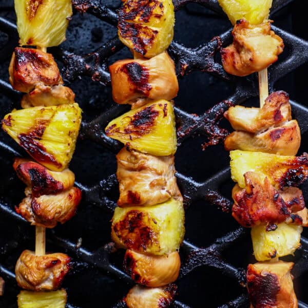 Pineapple Chicken Kebabs sizzle on the grill, their char marks enhancing the succulent chicken pieces and juicy pineapple chunks.