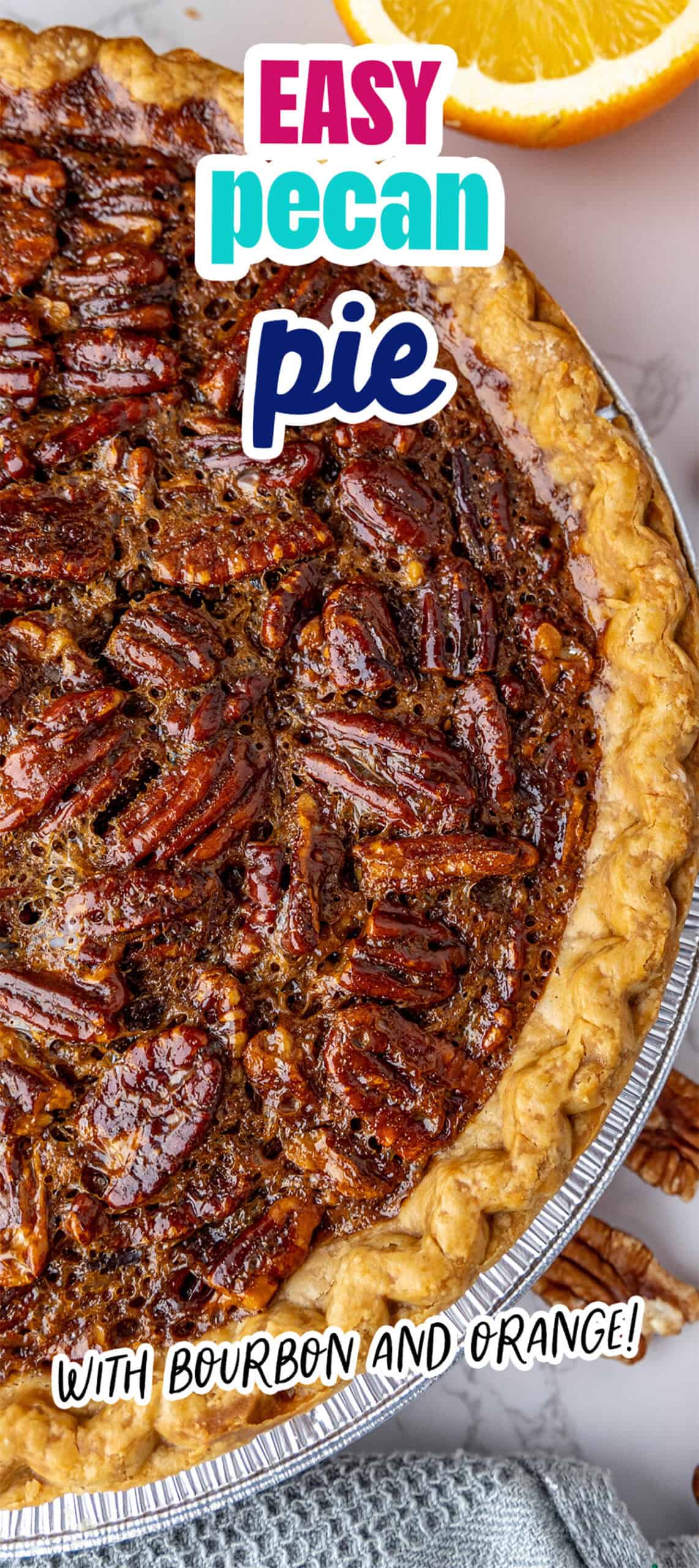 Close-up of a pecan pie with a text overlay reading "Easy pecan pie with bourbon and orange!" An orange slice and a blue cloth are visible beside the pie.