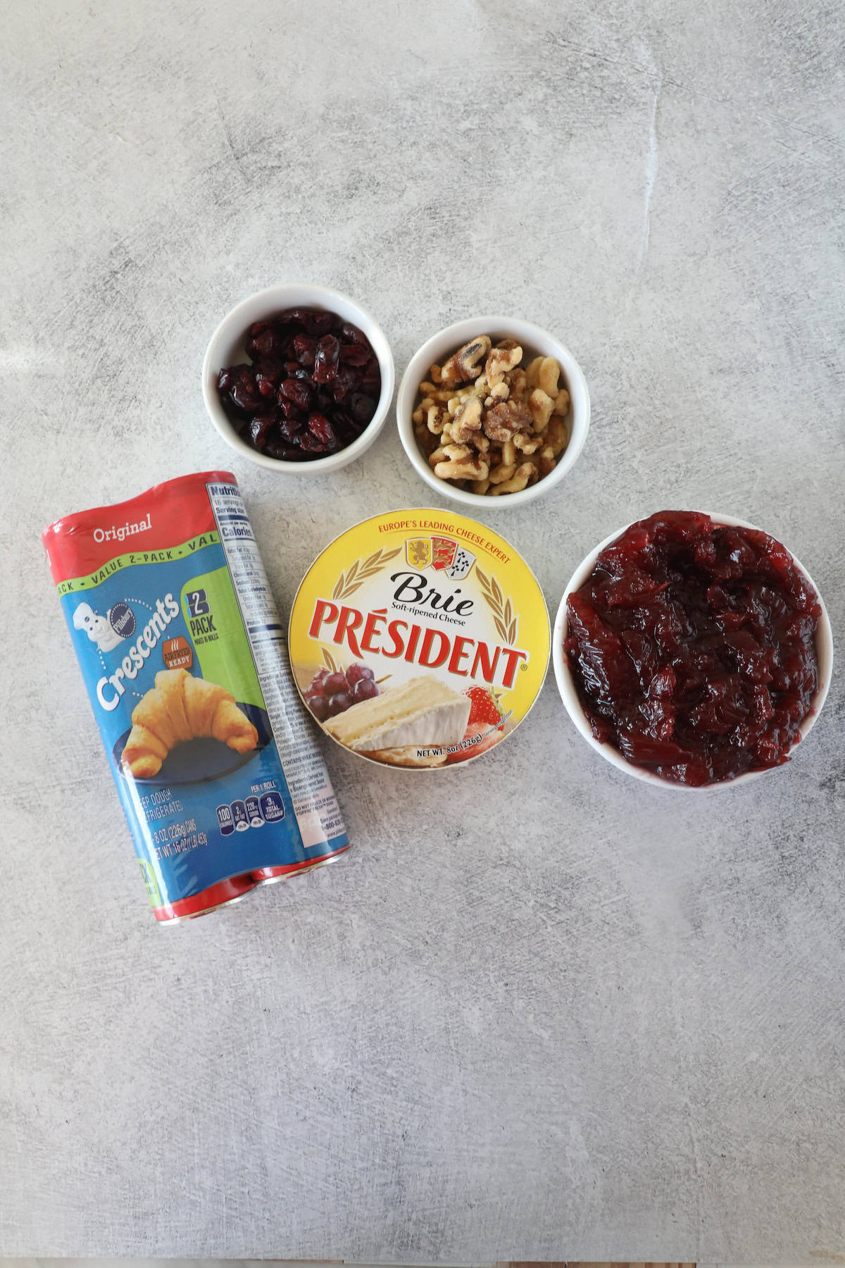 Create a delightful cranberry Brie wreath with just a can of crescent rolls, a round of Brie cheese, and a bowl of cranberry sauce. Add small bowls of walnuts and dried cranberries for an irresistible festive touch.