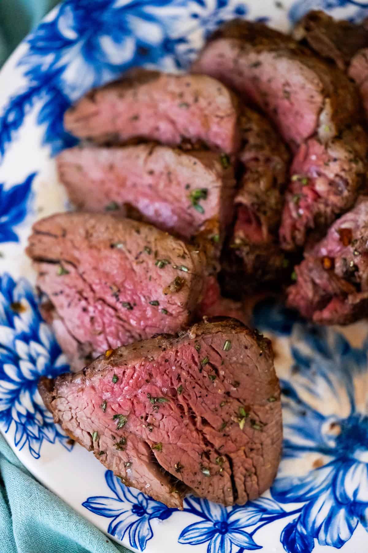 Slices of reverse sear roast beef on a white and blue floral plate.