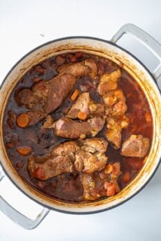 A pot of braised country-style ribs with carrots, enhanced by a rich, dark sauce and a hint of paprika.