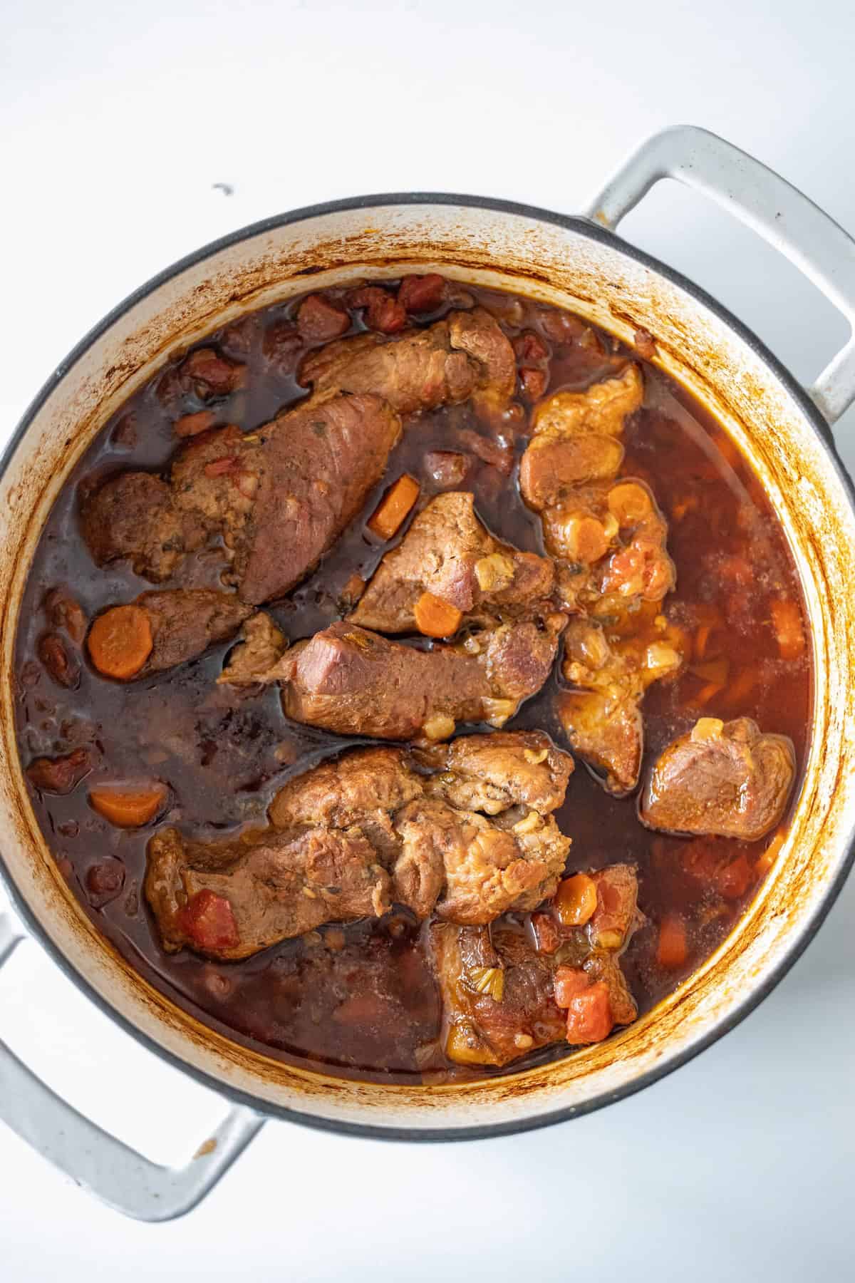 A pot of braised country-style ribs with carrots, enhanced by a rich, dark sauce and a hint of paprika.