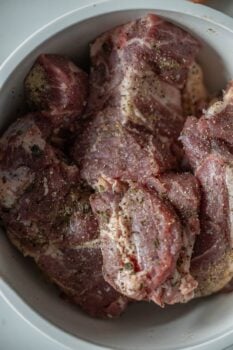 Braised, seasoned pieces of country style ribs with a hint of paprika rest invitingly in a white bowl.