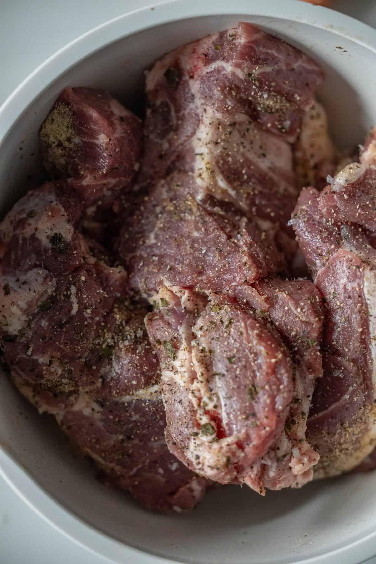 Braised, seasoned pieces of country style ribs with a hint of paprika rest invitingly in a white bowl.