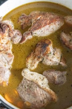 Braised country style ribs simmering in a pot with seasoned broth, enhanced by a hint of paprika.