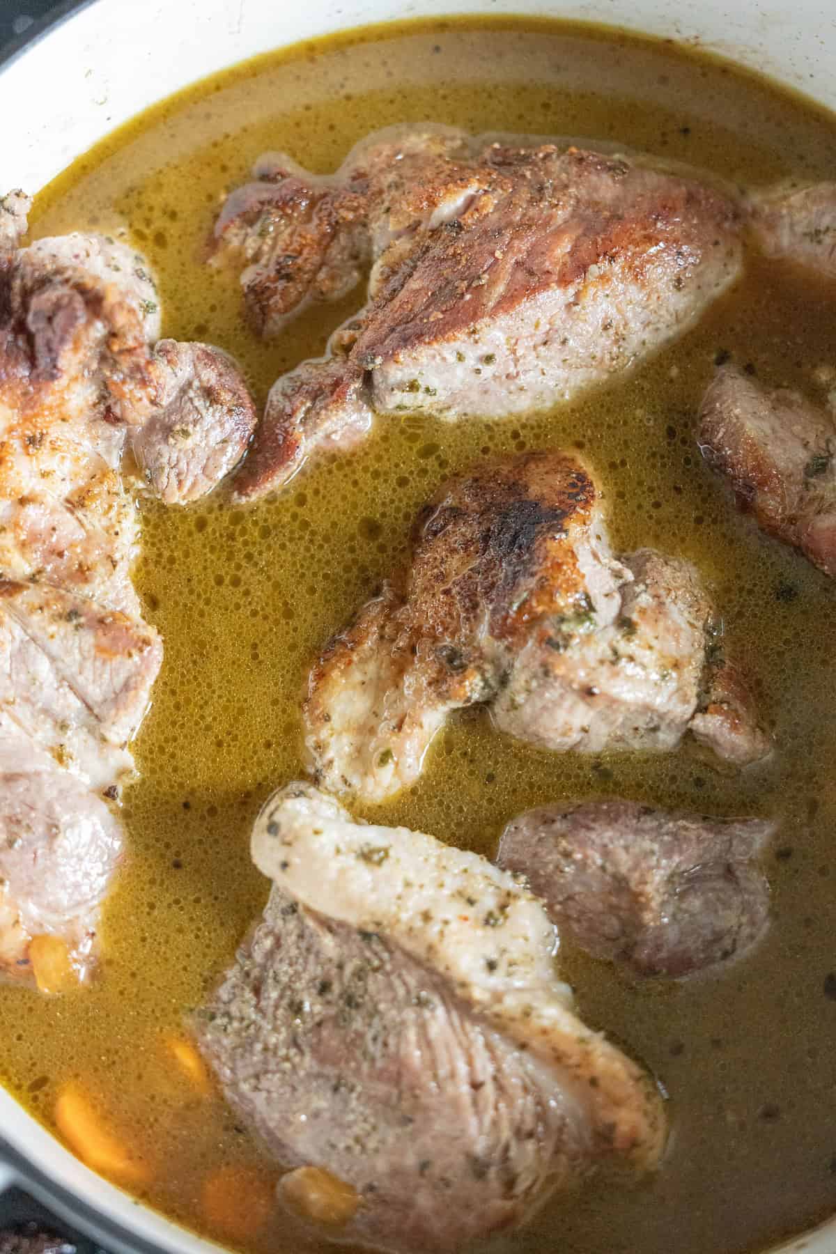 Braised country style ribs simmering in a pot with seasoned broth, enhanced by a hint of paprika.