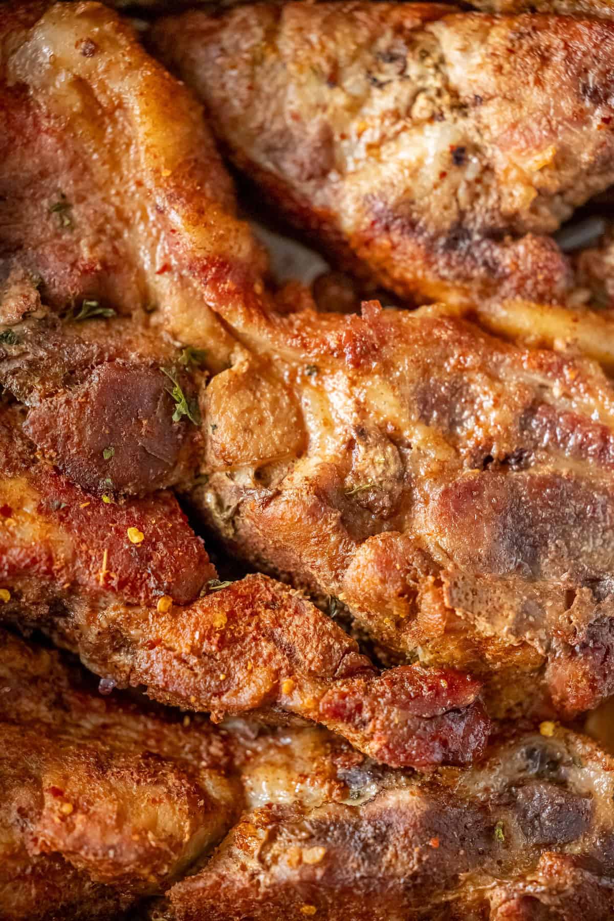 Close-up of crispy, golden-brown fried pork pieces with visible herbs and spices, reminiscent of savory oven-roasted country style ribs.