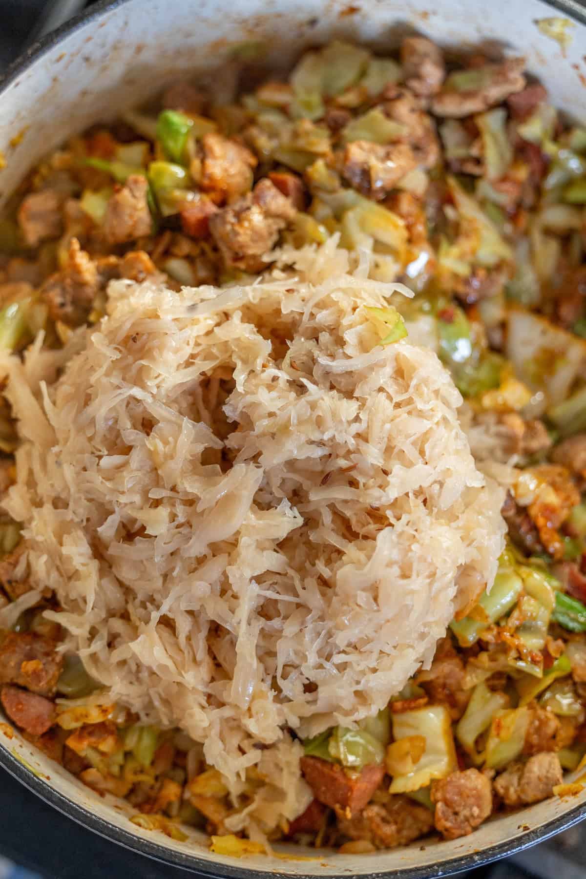 In a large pot, create a delicious Polish bigos by layering sauerkraut over cooked sausage, cabbage, and vegetables. This traditional hunters stew is hearty and flavorful, perfect for a cozy meal.