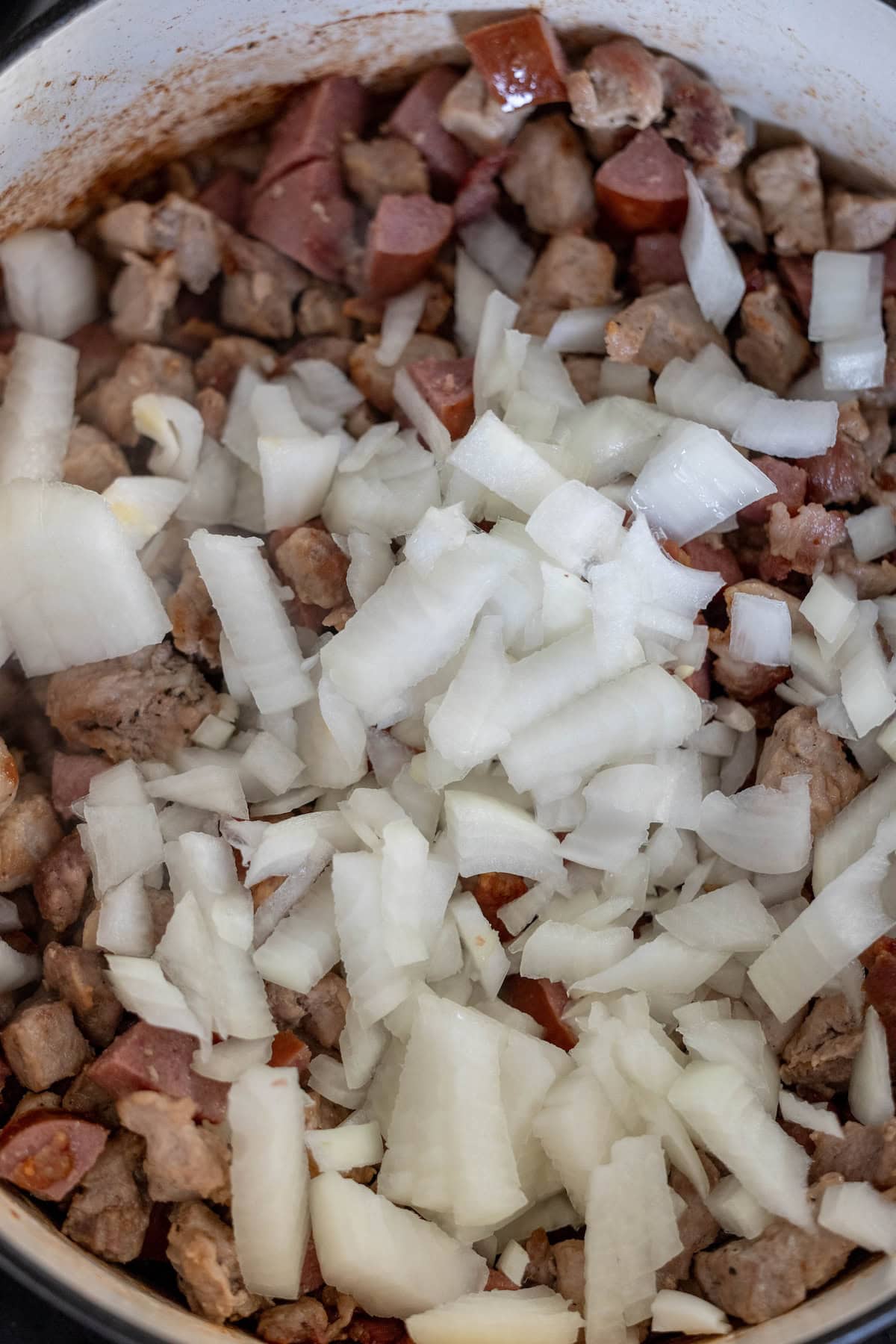 Chopped onions and diced meat simmer harmoniously in a pot, creating a delightful Polish bigos stew.