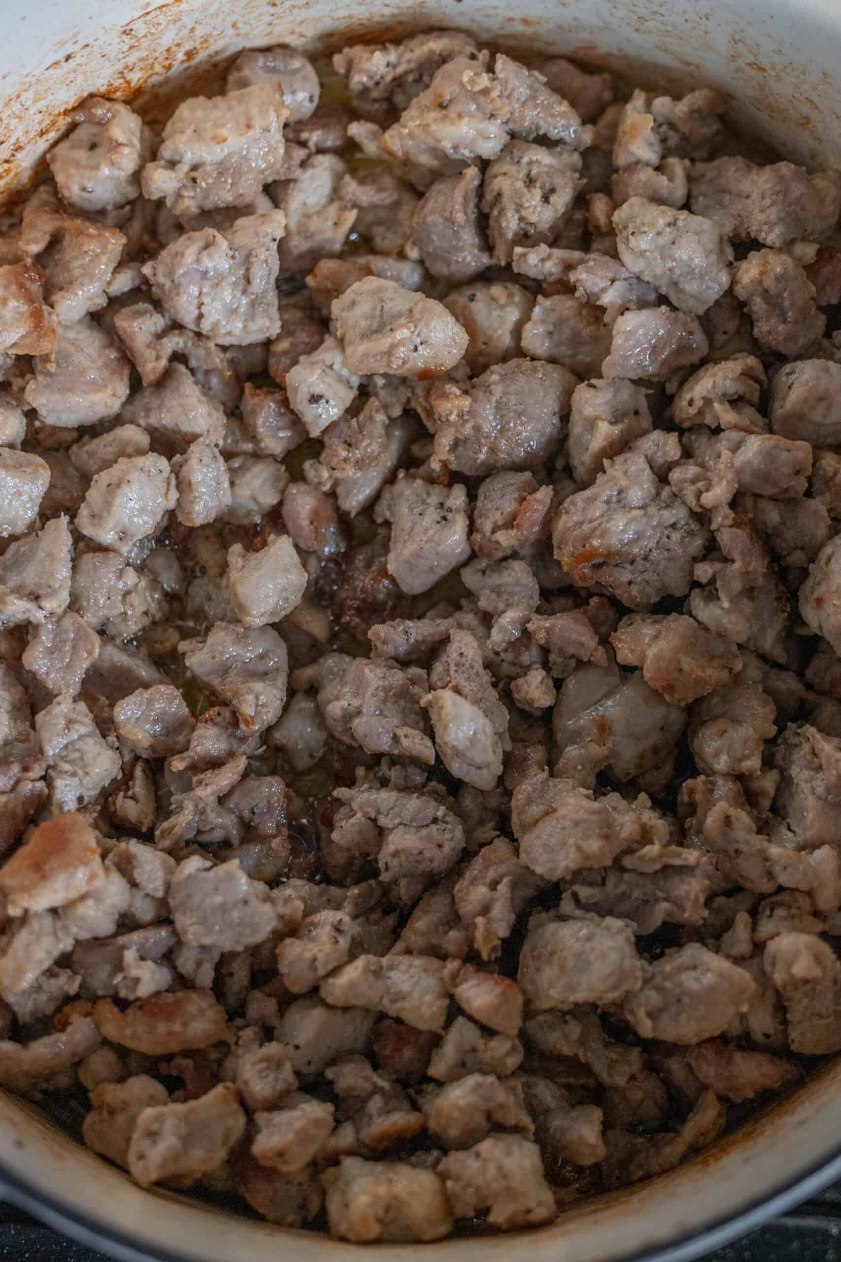 A hearty pot of Polish Bigos, also known as Hunters Stew, features tender chunks of cooked meat mingling with rich flavors, creating a warm and comforting dish.