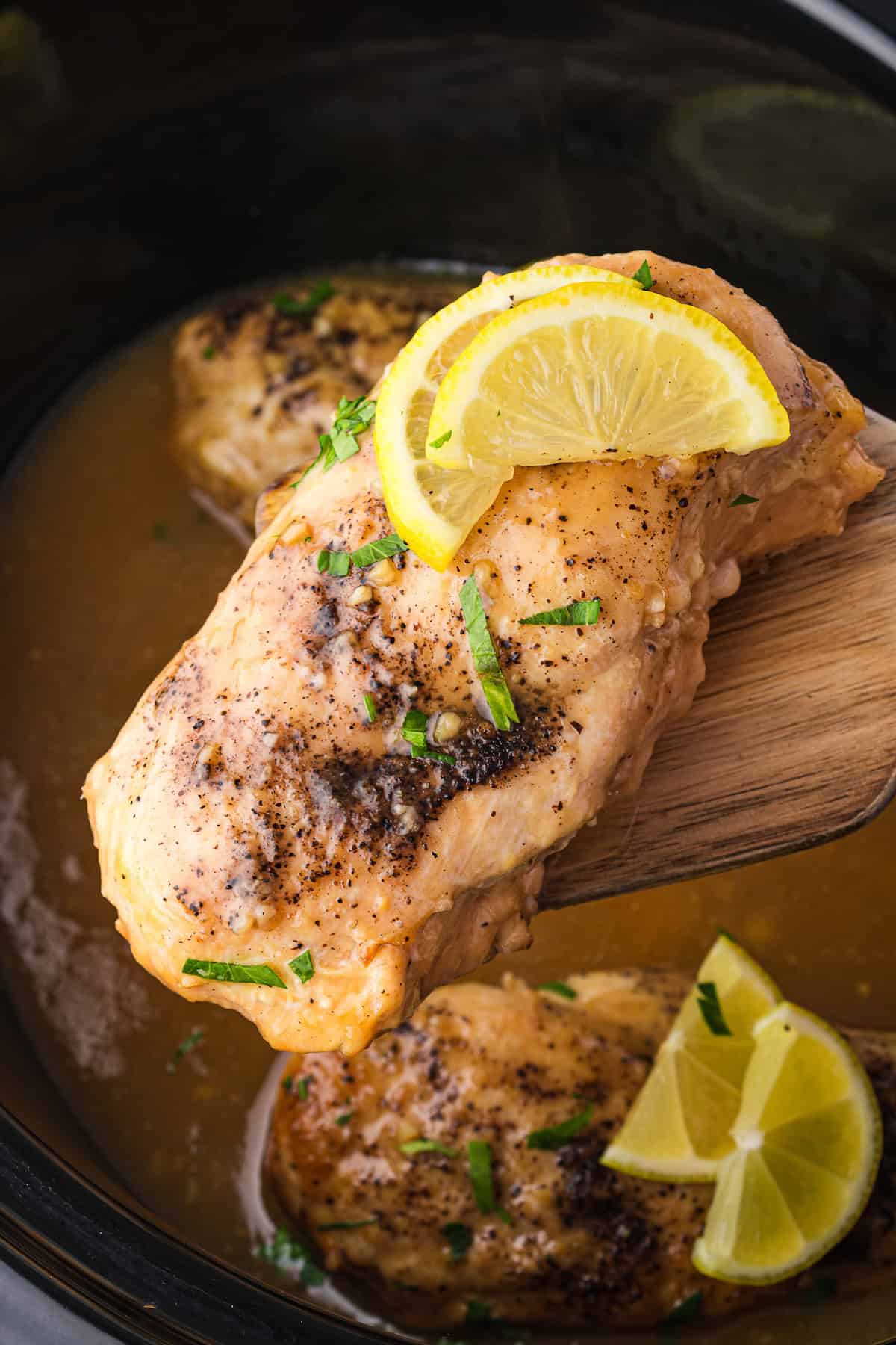 Savor the delightful taste of Lemonade Chicken, featuring cooked chicken breast with zesty lemon slices and aromatic herbs, all perfectly prepared in a slow cooker.