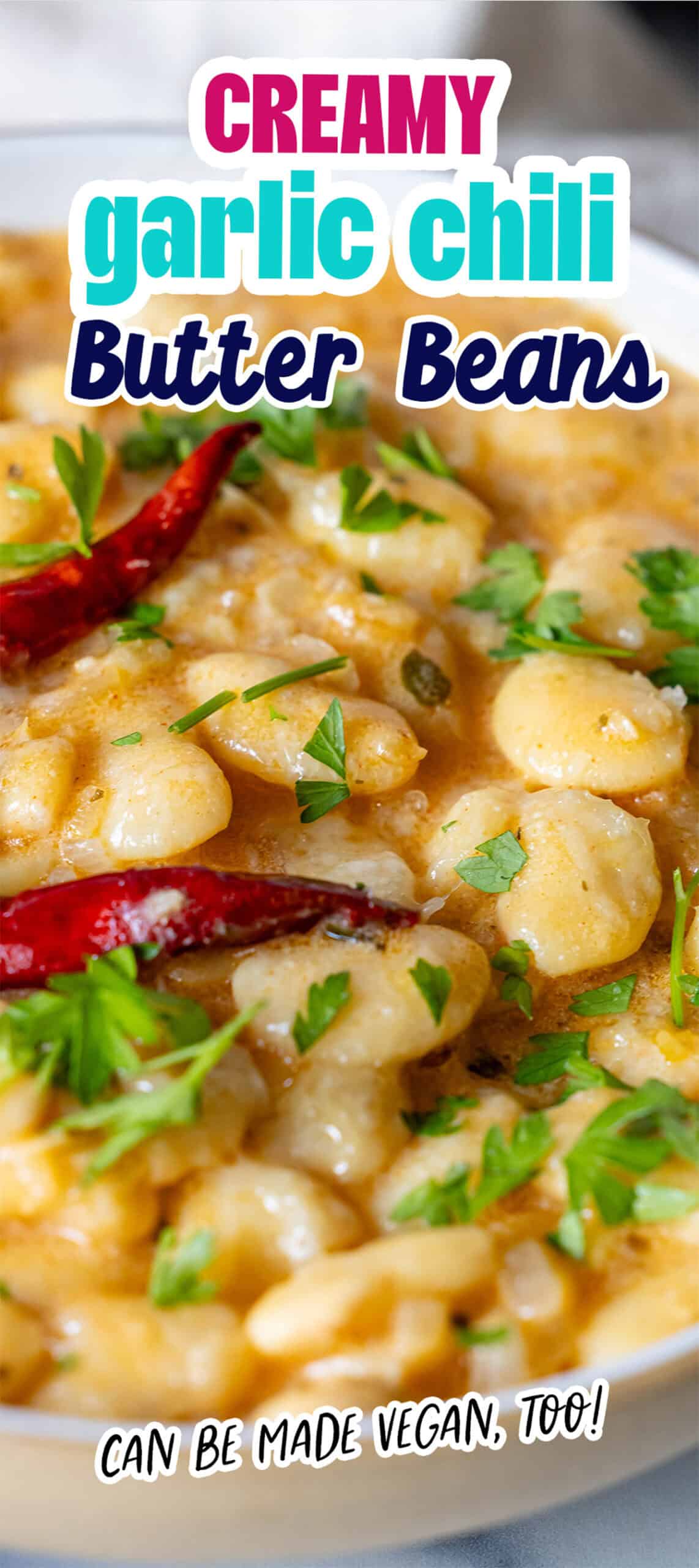 Close-up of a dish with creamy, garlic-infused chili butter beans, garnished with herbs and whole red chilies. Labeled "Creamy Garlic Chili Butter Beans," it can easily be made vegan too!.