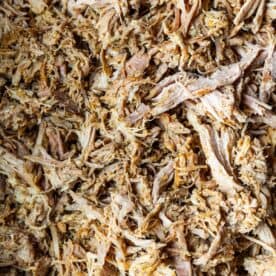 Close-up of Slow Cooker Carnitas, showing shredded cooked meat with tender strands and a slightly browned texture.