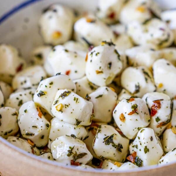 A close-up of a bowl filled with marinated mozzarella balls coated in herbs and spices—an irresistible Mozzarella Appetizer perfect for any gathering.