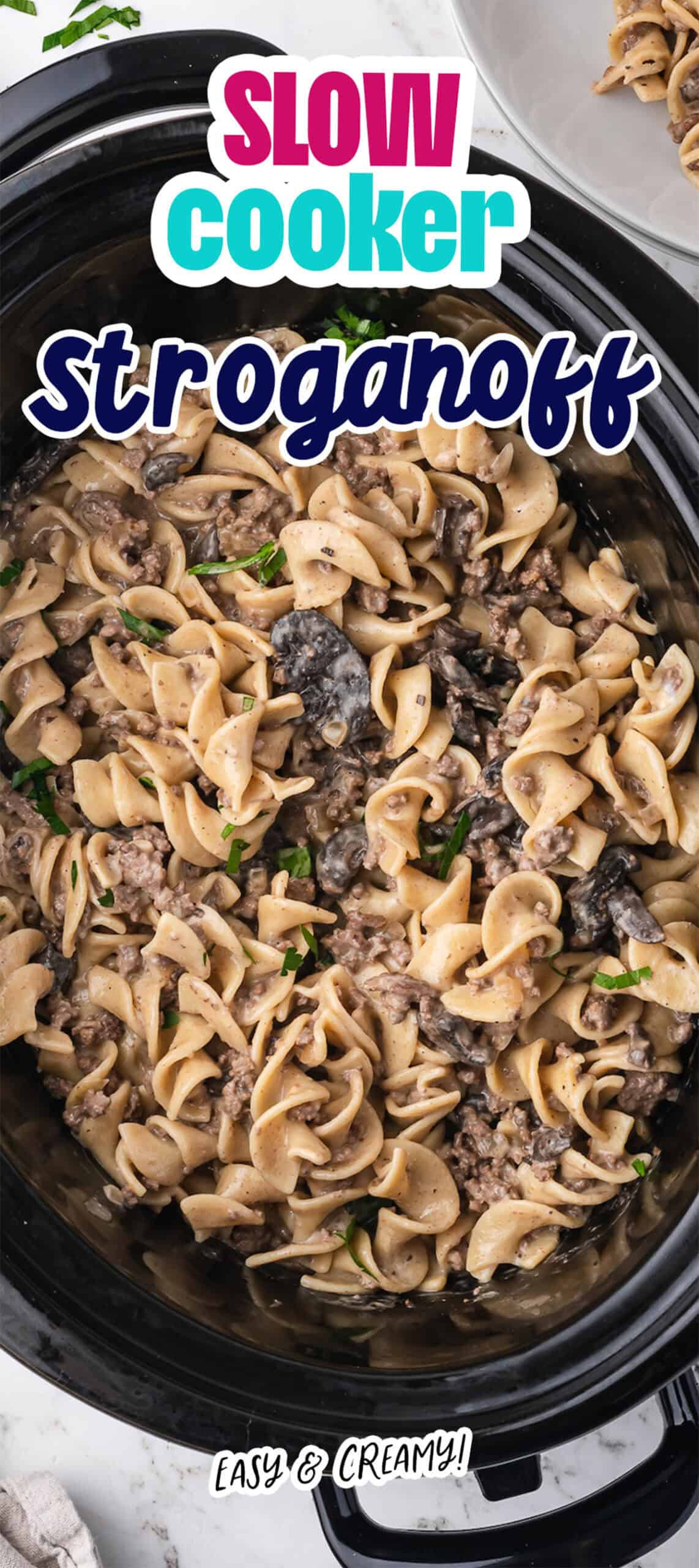 Overhead view of Slow Cooker Beef Stroganoff with egg noodles, mushrooms, and creamy sauce in a slow cooker, topped with a text overlay reading "Slow Cooker Stroganoff.