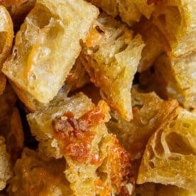 Close-up view of several pieces of bread with melted cheese, showing a crispy, golden-brown texture—perfect for making homemade croutons.