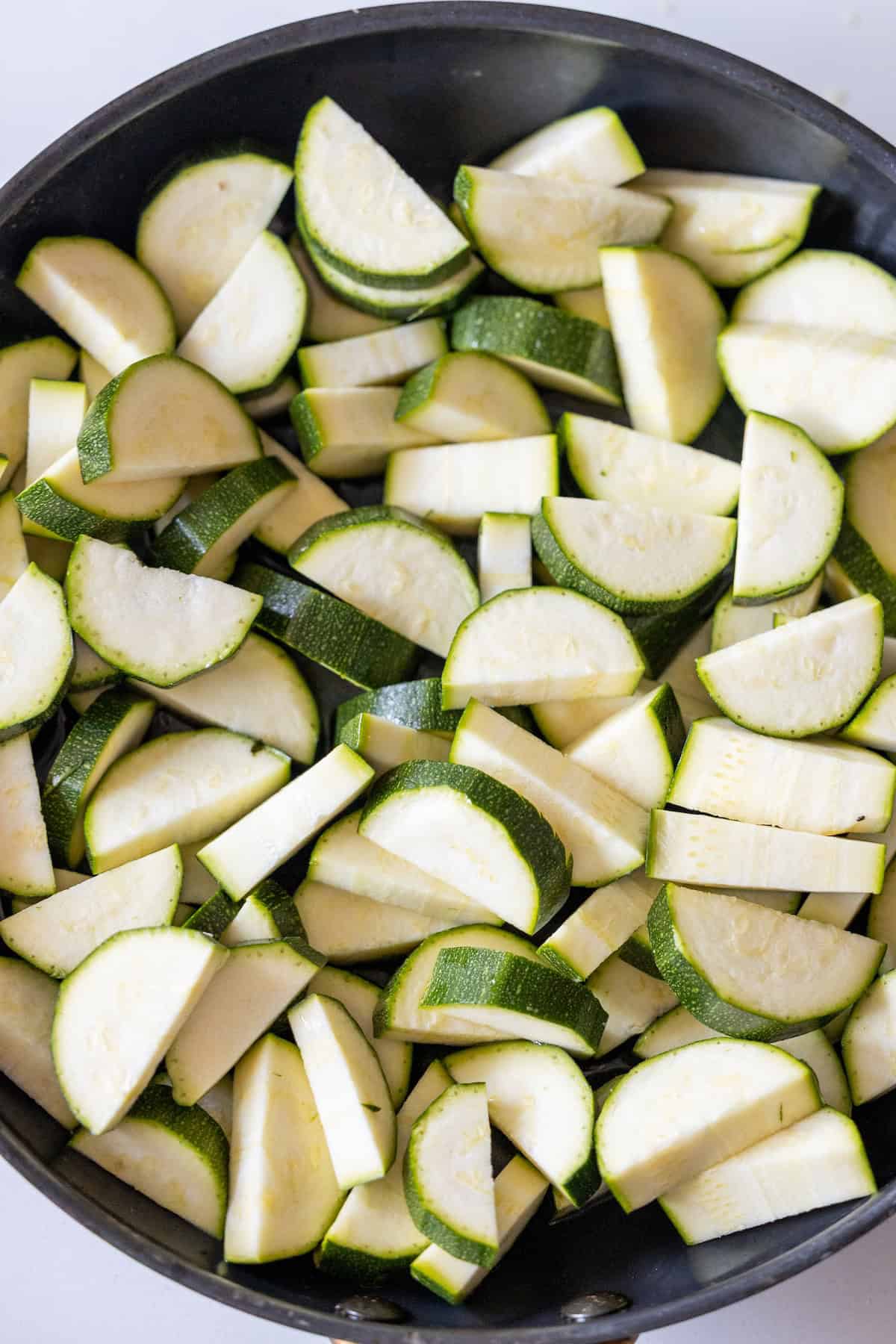 Sliced zucchini pieces in a black pan, ready to be cooked for your next marry me recipe.