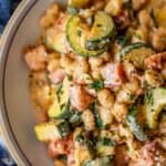 Close-up of a bowl containing a creamy mixture of beans, zucchini slices, diced tomatoes, and herbs—flavors that truly marry me in every bite.