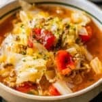 A close-up of Cabbage Roll Soup, a healthy soup recipe featuring ground meat, diced tomatoes, herbs, and cabbage in a flavorful red broth.