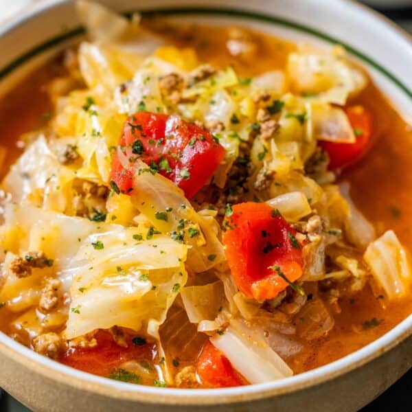 A close-up of Cabbage Roll Soup, a healthy soup recipe featuring ground meat, diced tomatoes, herbs, and cabbage in a flavorful red broth.