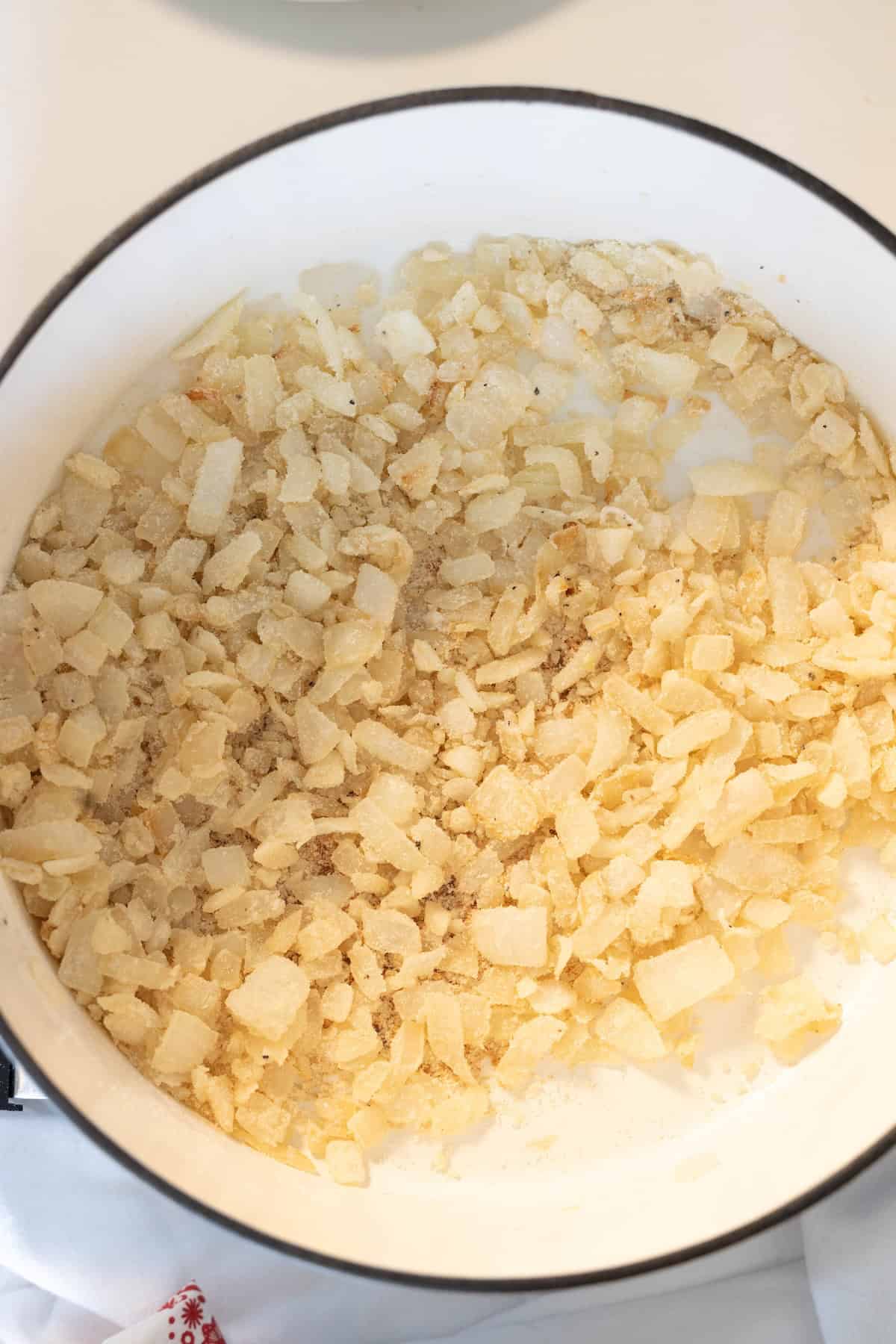 Chopped onions are sautéing in a white pot with oil or butter, turning translucent and beginning to caramelize—the perfect base for a hearty Irish Seafood Chowder.
