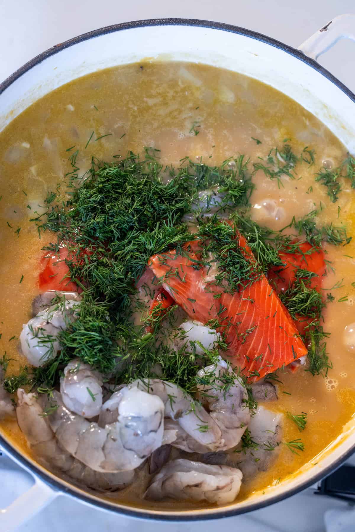 A pot of Irish Seafood Chowder with shrimp, salmon, fresh dill, and a light broth, photographed from above.
