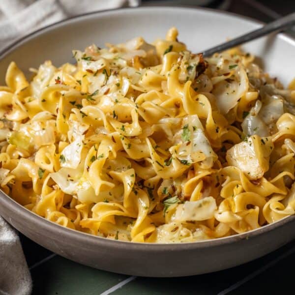 A bowl of cooked egg noodles tossed with sautéed cabbage and garnished with fresh chopped herbs creates a classic cabbage and noodles dish.