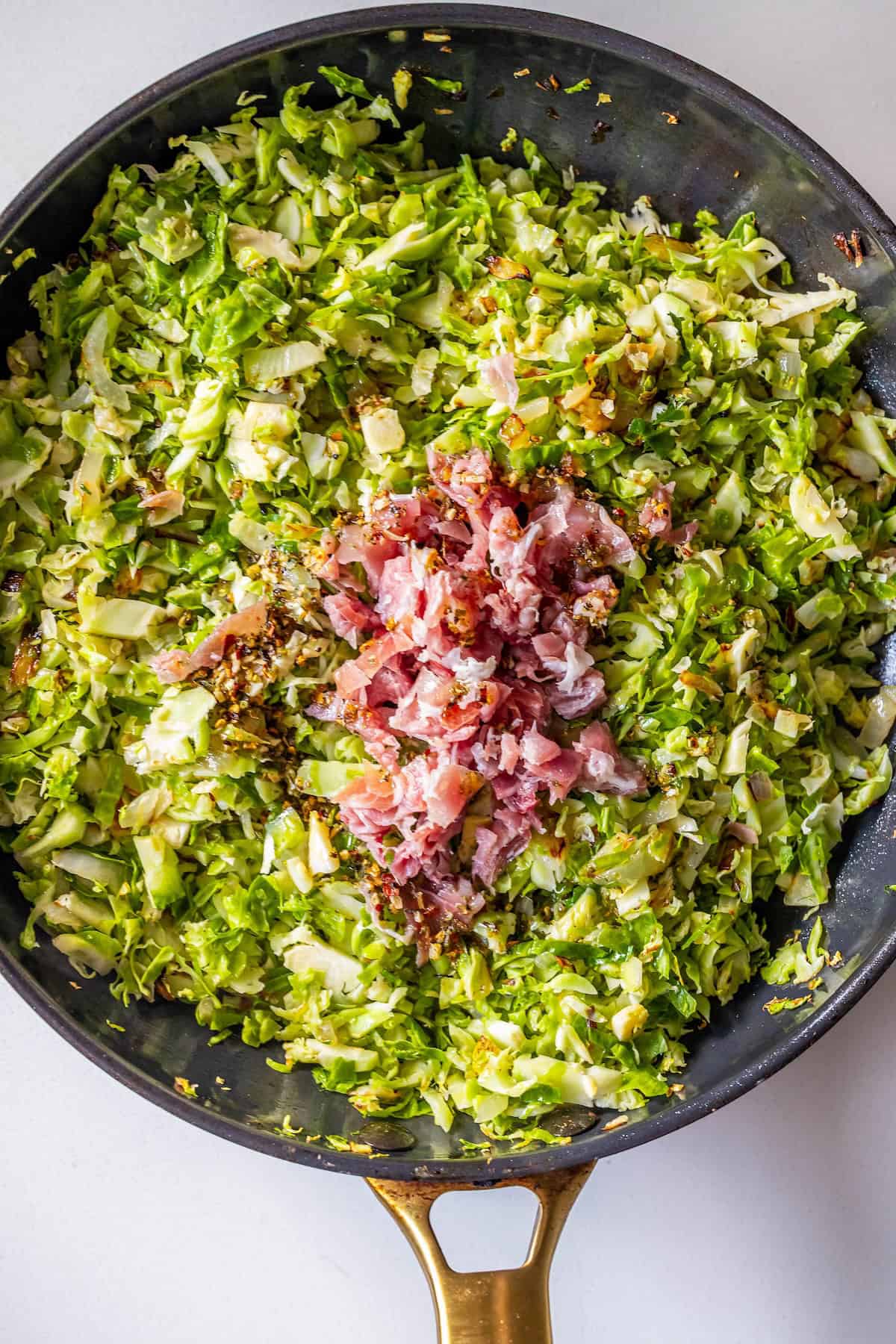 Brussels Sprouts Hash with diced ham sizzles in a black skillet with a gold handle, creating a savory, colorful skillet hash perfect for any meal.