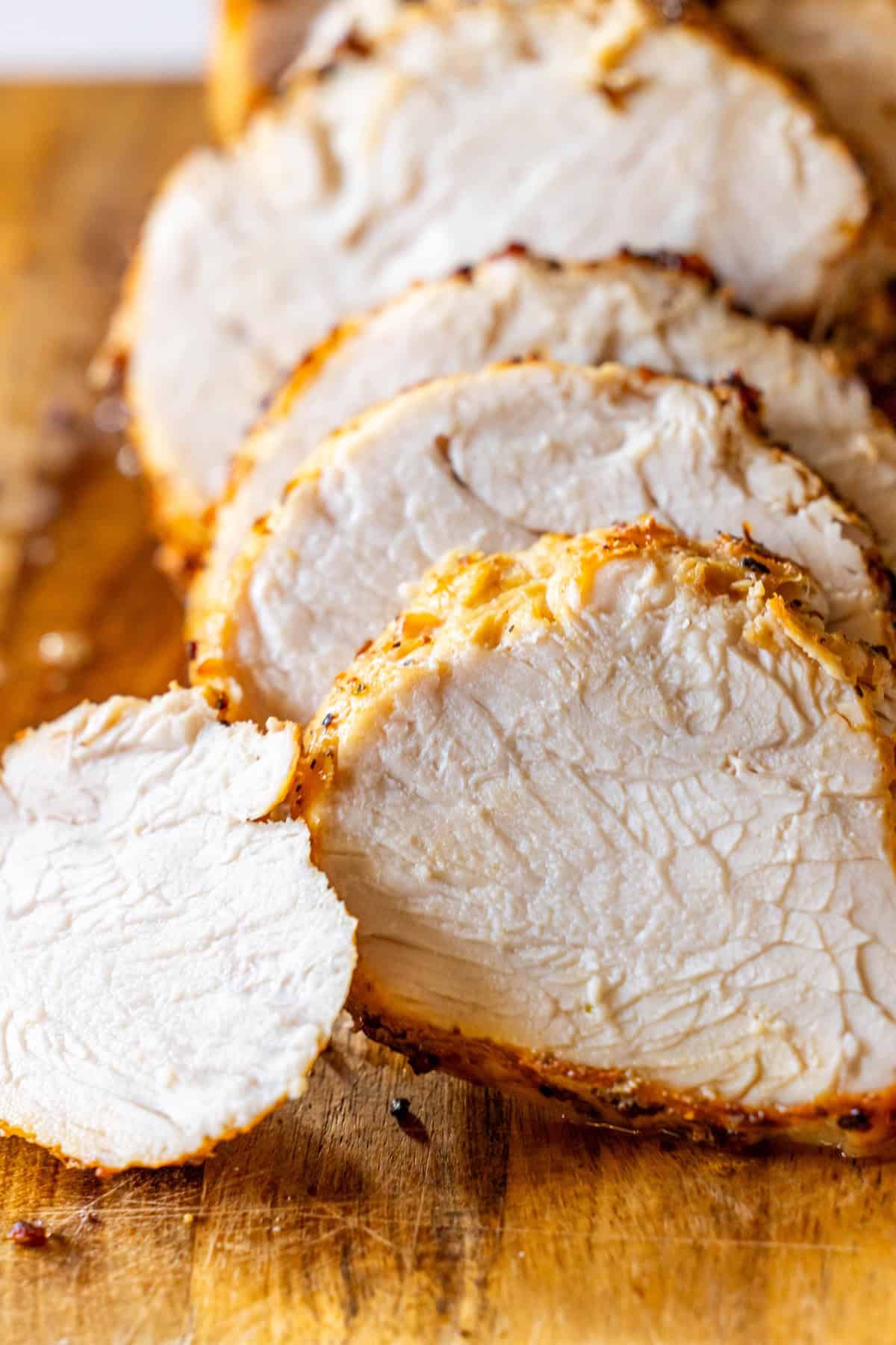 Sliced air fryer turkey breast displayed on a wooden cutting board.