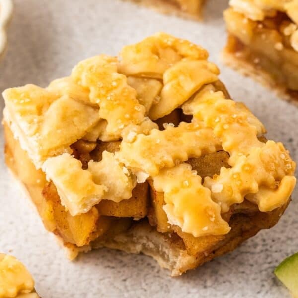 A close-up of delicious Apple Pie Bars, featuring a square slice with a golden-brown lattice crust and sugar sprinkled on top.