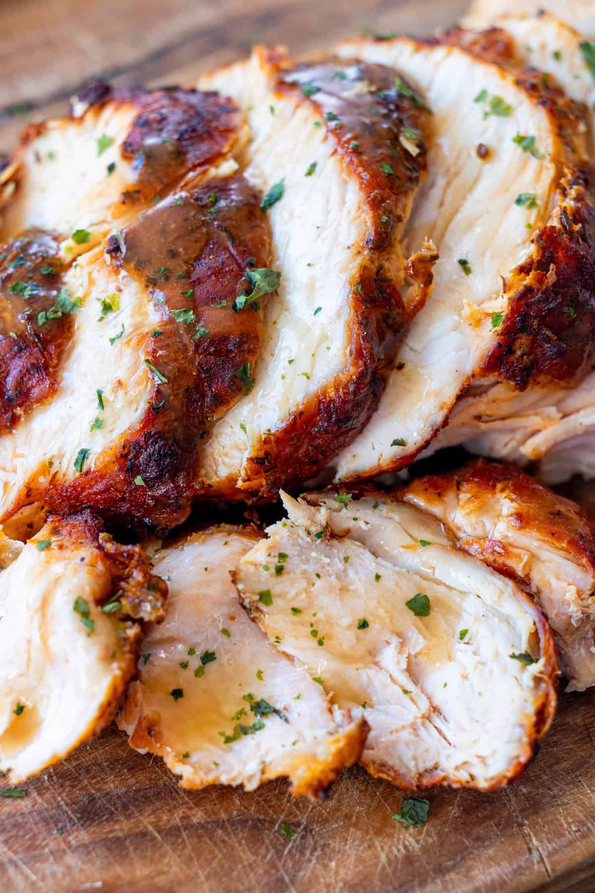 Sliced, cooked turkey breast garnished with chopped herbs on a wooden cutting board—perfectly tender and flavorful from the air fryer.