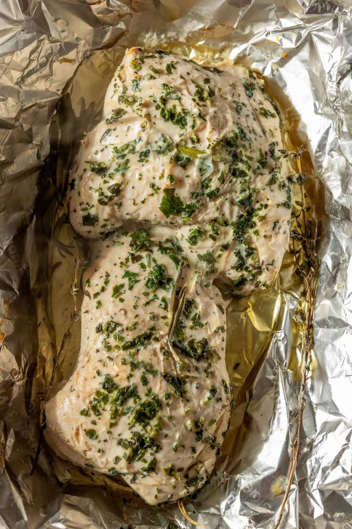 Cooked chicken breasts seasoned with herbs and spices, resting on crumpled aluminum foil with visible juices—perfect inspiration for an Easy Turkey Recipe like baked turkey tenderloin.
