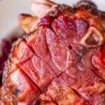 Close-up of a Cranberry Brandy Glazed Ham with a crosshatch pattern cut into the surface and visible bone.
